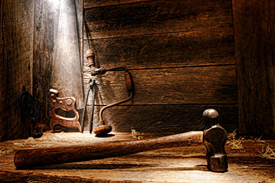 antique carpentry hand tools on a wooden table in an old barn with a beam of sunlight shining on them