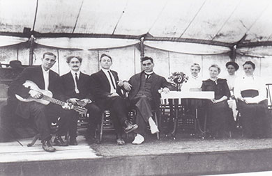 a black and white image of Dr. John G. Lake in a tent with other men and women hosting a divine healing room