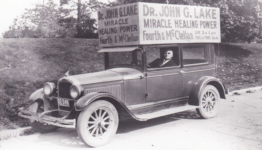 a vintage black and white image of a car advertising Dr. John G. Lake's miracle healing power